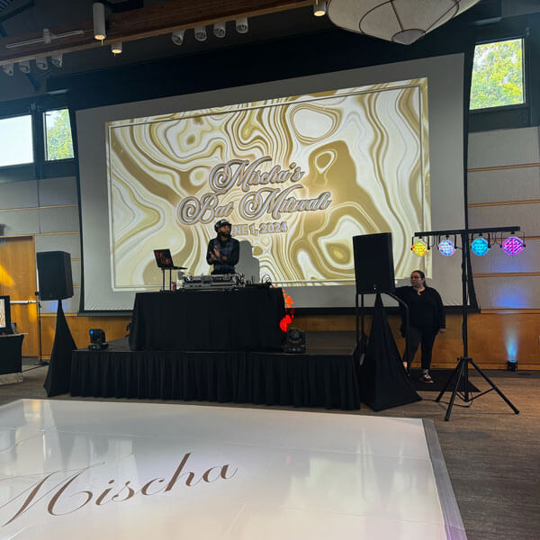 A vibrant dance floor in Dallas, TX, featuring a DJ and a large screen for the event